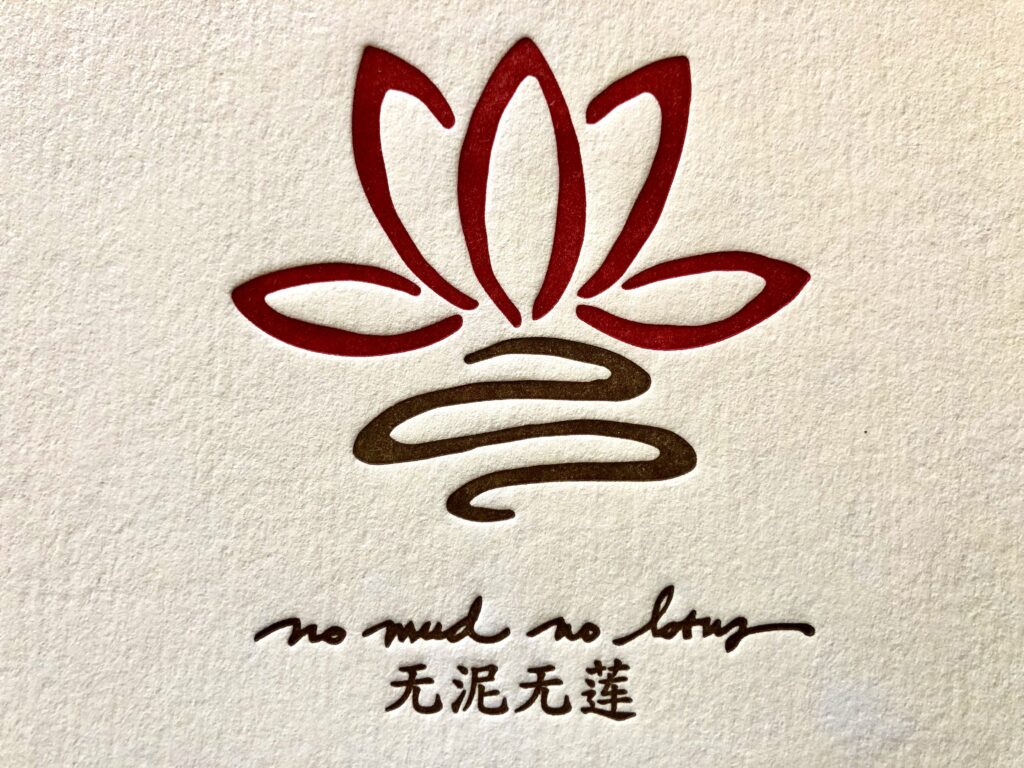 Letterpress art by Sophy Wong with a lotus flower and phrase "no mud no lotus" in English and Chinese.